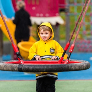 boy wearing a rain coat on a playground