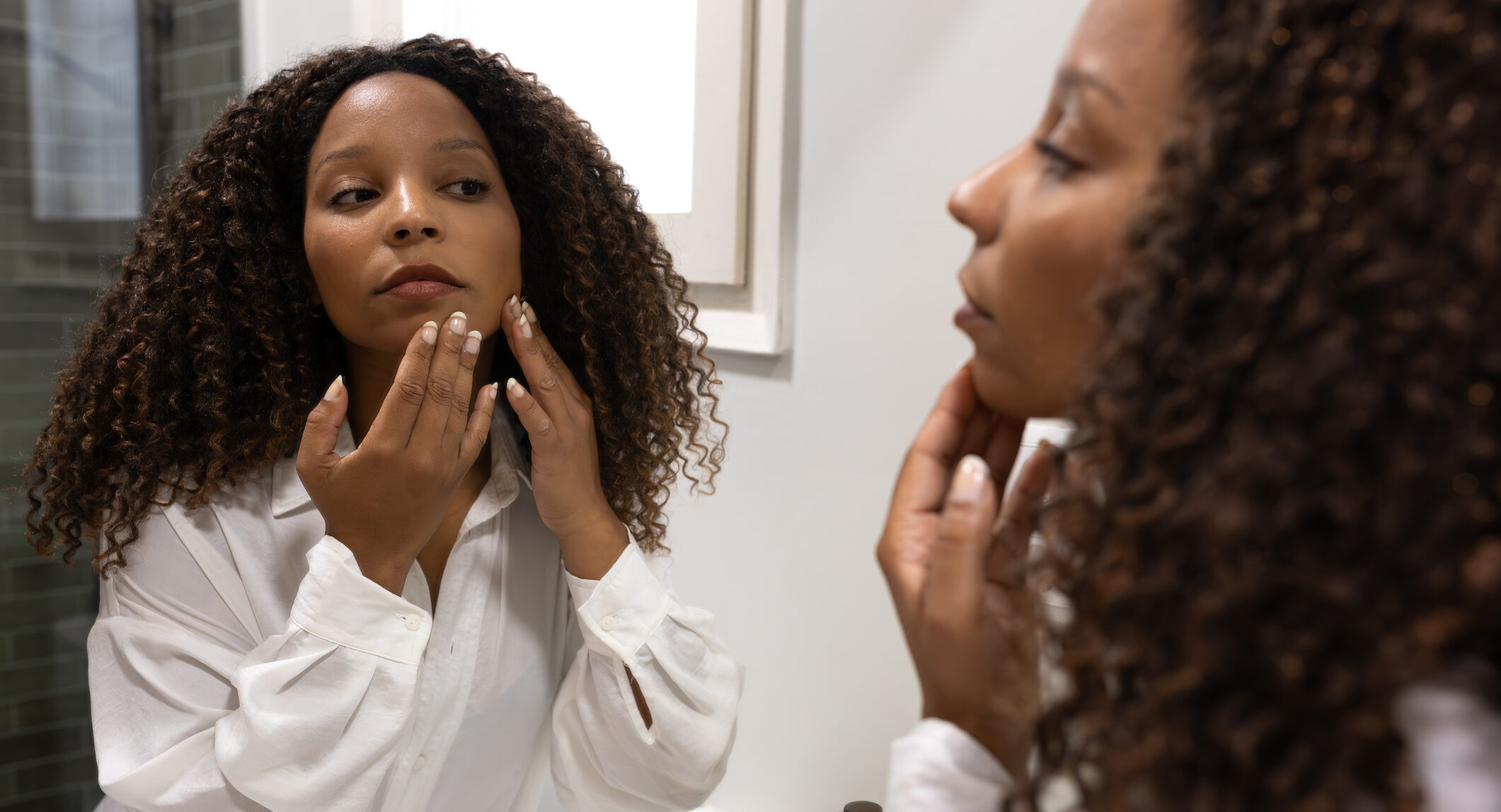 Woman checking facial skin in mirror